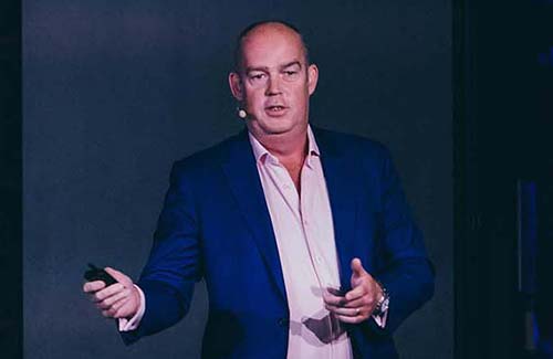 Adam Banks speaking on stage.